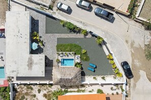 Eine Vogelperspektive eines Anwesens mit Schwimmbad, Liegestühlen und einem Parkplatz.