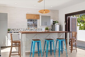 Een moderne keuken met een centraal eiland, barstoelen en een hanglamp.