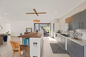 Eine moderne Küche mit einer Holzinsel, grauen Schränken und einem Deckenventilator.