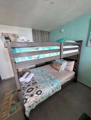 A bunk bed with patterned bedding, a welcome pillow, and a small decorative item on the headboard. - Waterfront Condo, Private Marina Island,
Fajardo (Fajardo)