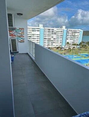A balcony with a view of a hotel building and a pool area. - Waterfront Condo, Private Marina Island,
Fajardo (Fajardo)