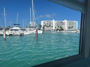 A marina with multiple boats docked, a large hotel building in the background, and a clear blue sky. - Waterfront Condo, Private Marina Island,
Fajardo (Fajardo)