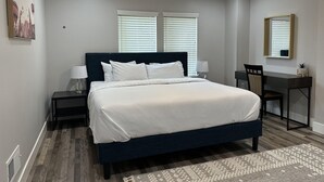 Un dormitorio con cama, mesitas de noche, un escritorio y una silla.