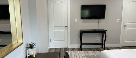 A hotel room with a bed, a TV mounted on the wall, a small table, and a potted plant.