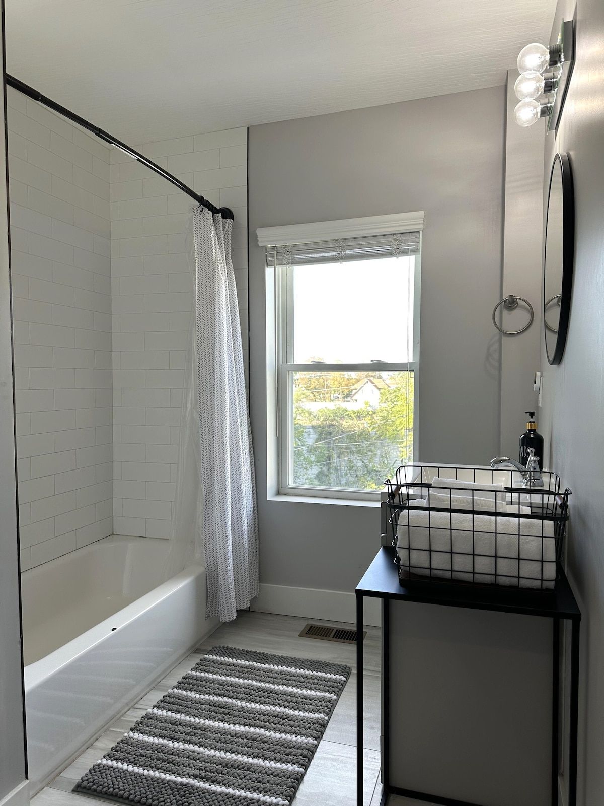 Une salle de bain avec une douche, une fenêtre, un porte-serviettes et un lavabo.