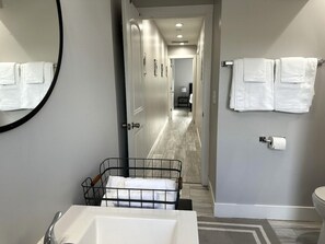 Een moderne badkamer met een witte badkuip, een zwart metalen rek, een toilet en een spiegel aan de muur.