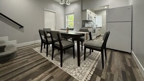 Una cocina moderna con comedor, piso de madera y una escalera.