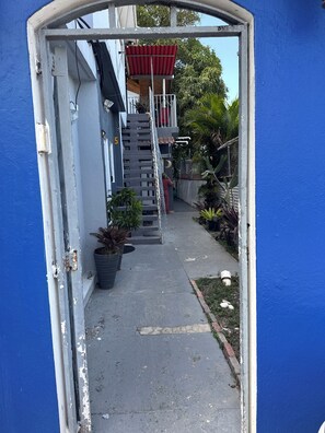 A narrow pathway leading to a building with a red roof and a staircase. - 7 minutes from the airport (Carolina)
