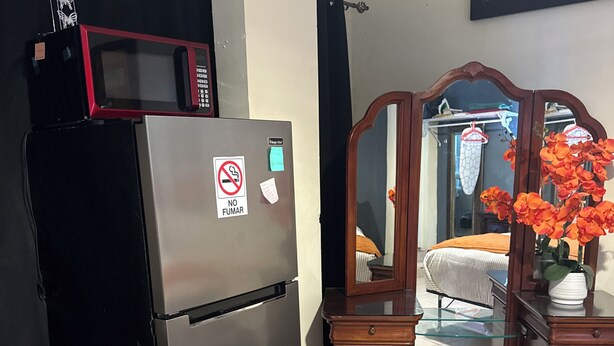 Una cocina con un refrigerador de acero inoxidable, un aparador de madera con cajones y un espejo.