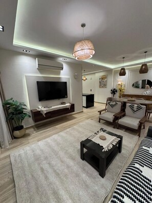 A modern living room with a flat-screen TV, a coffee table, and seating. - 3-Bedroom Apartment with AC, Near Grand Egyptian Museum, Wasal Compound. (Cairo Governorate)