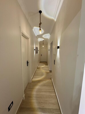 Ein Korridor mit weißen Wänden, Holzboden und einer Deckenleuchte.