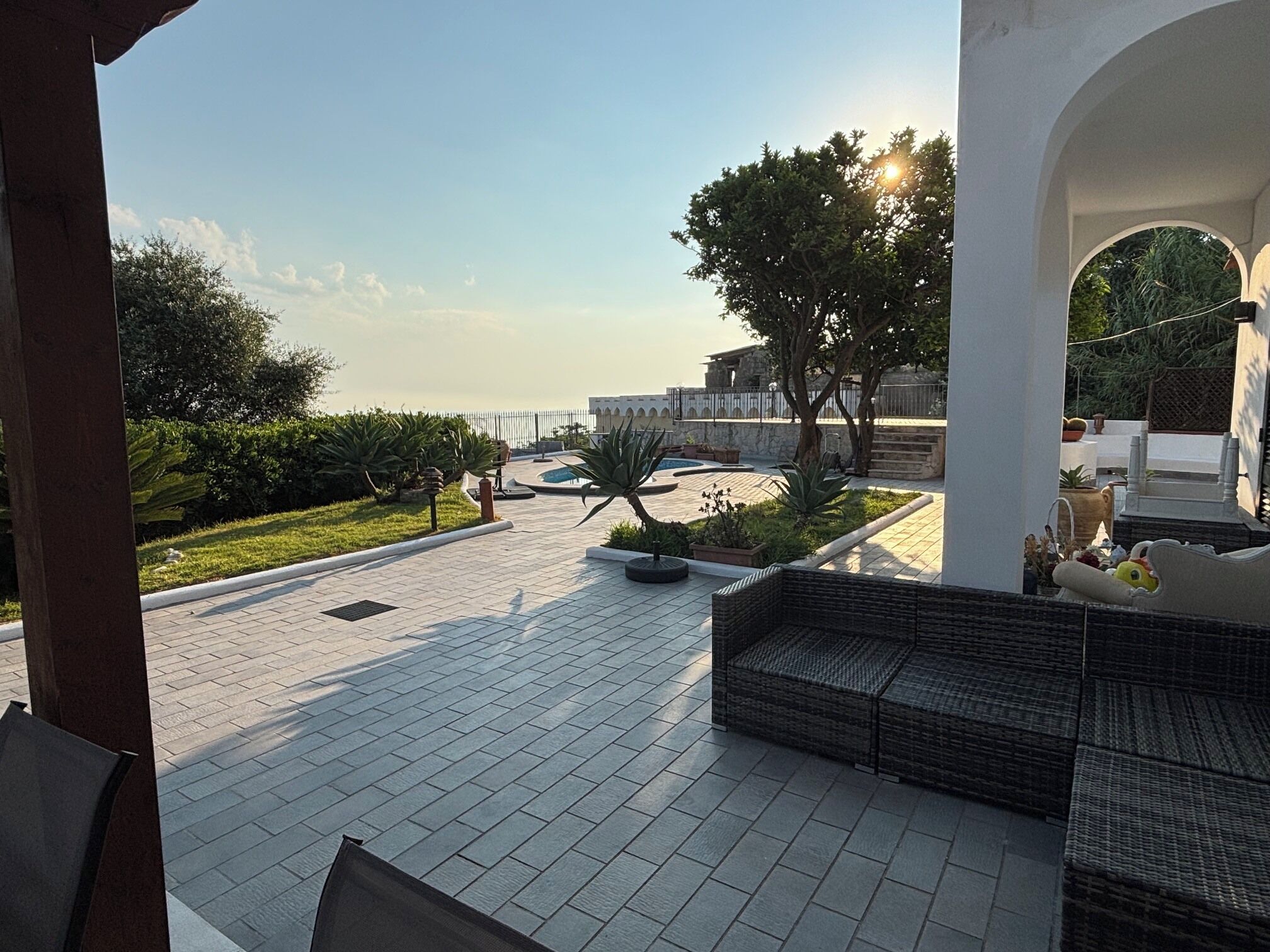 An outdoor patio area with a seating arrangement, a pool, and a view of a building with a stone facade.