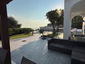 An outdoor patio area with a seating arrangement, a pool, and a view of a building with a stone facade.