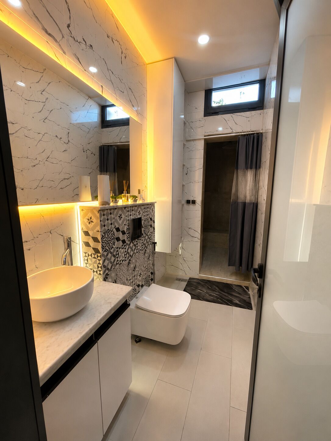 A modern bathroom with a marble vanity, a toilet, and a shower area.