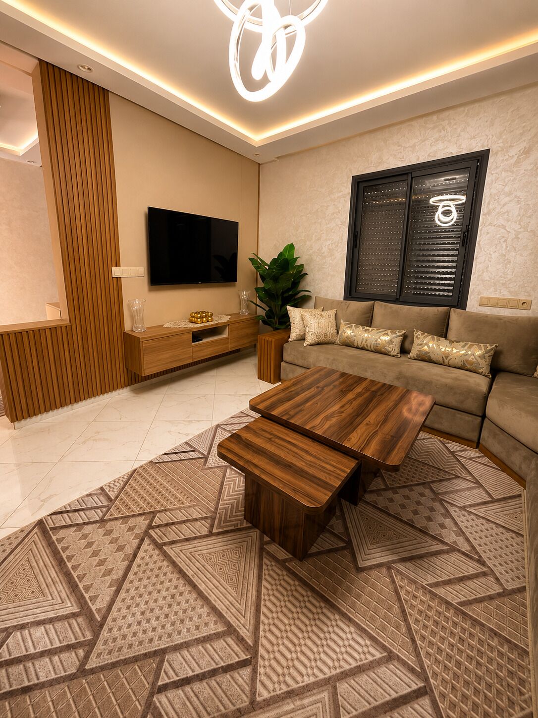 Una sala de estar moderna con una televisión de pantalla plana, una mesa de centro de madera, un sofá y una alfombra estampada.