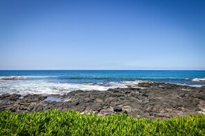 Stunning coastal setting with rocky shoreline and vibrant ocean views, offering a serene backdrop to the property. - Kona Reef F22: Top-Floor Condo with Ocean Views (Kailua-Kona)