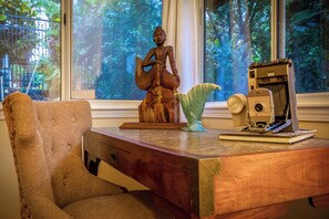 Un bureau en bois orné d’une statue, d’un appareil photo Polaroid vintage et d’un vase vert.
