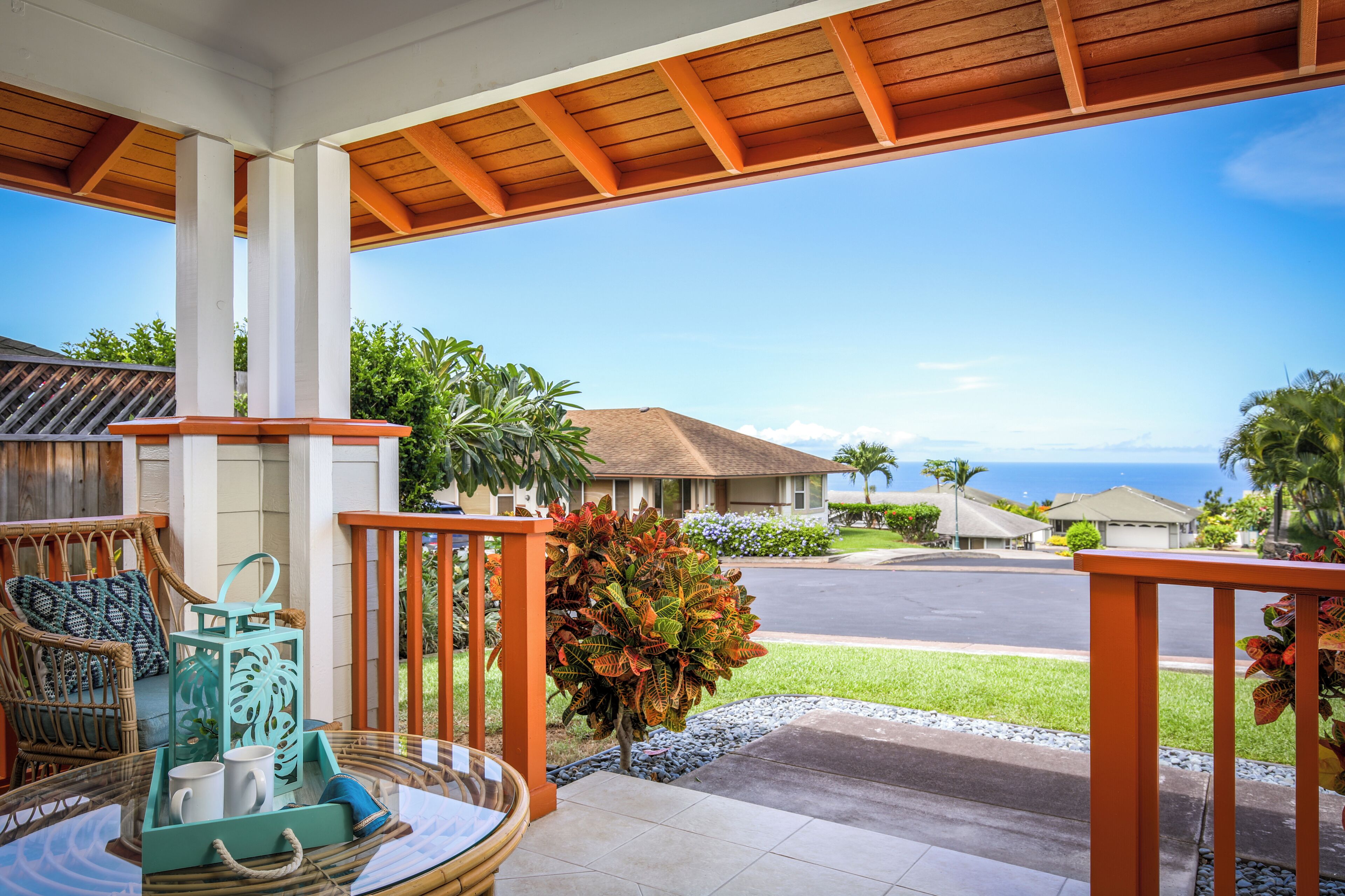 A covered porch with a view of a residential street and ocean.