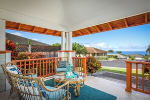 A covered outdoor seating area with wicker furniture and a view of the ocean. - Hale Kona: Home - Ocean Views/Hot Tub/Private Yard (Kailua-Kona)