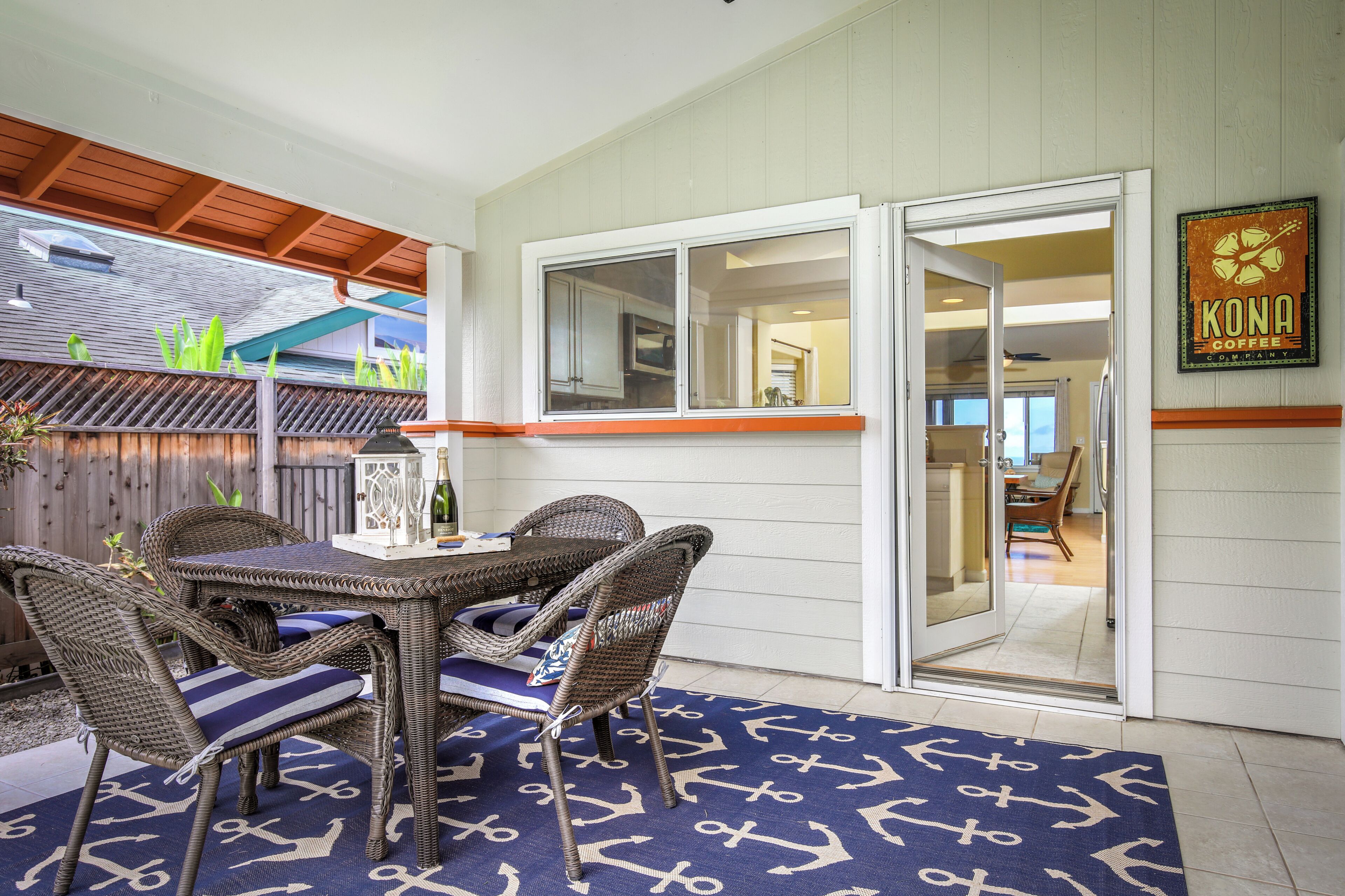 A dining area with wicker furniture and a blue rug with anchor patterns.