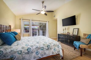 A bedroom with a bed, a dresser, a TV, and a ceiling fan. - Hale Kona: Home - Ocean Views/Hot Tub/Private Yard (Kailua-Kona)