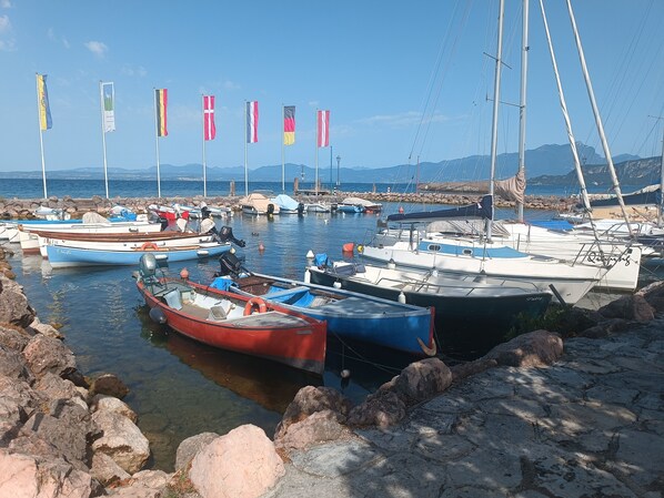 Un port de plaisance où sont amarrés différents types de bateaux, une côte rocheuse et des drapeaux.
