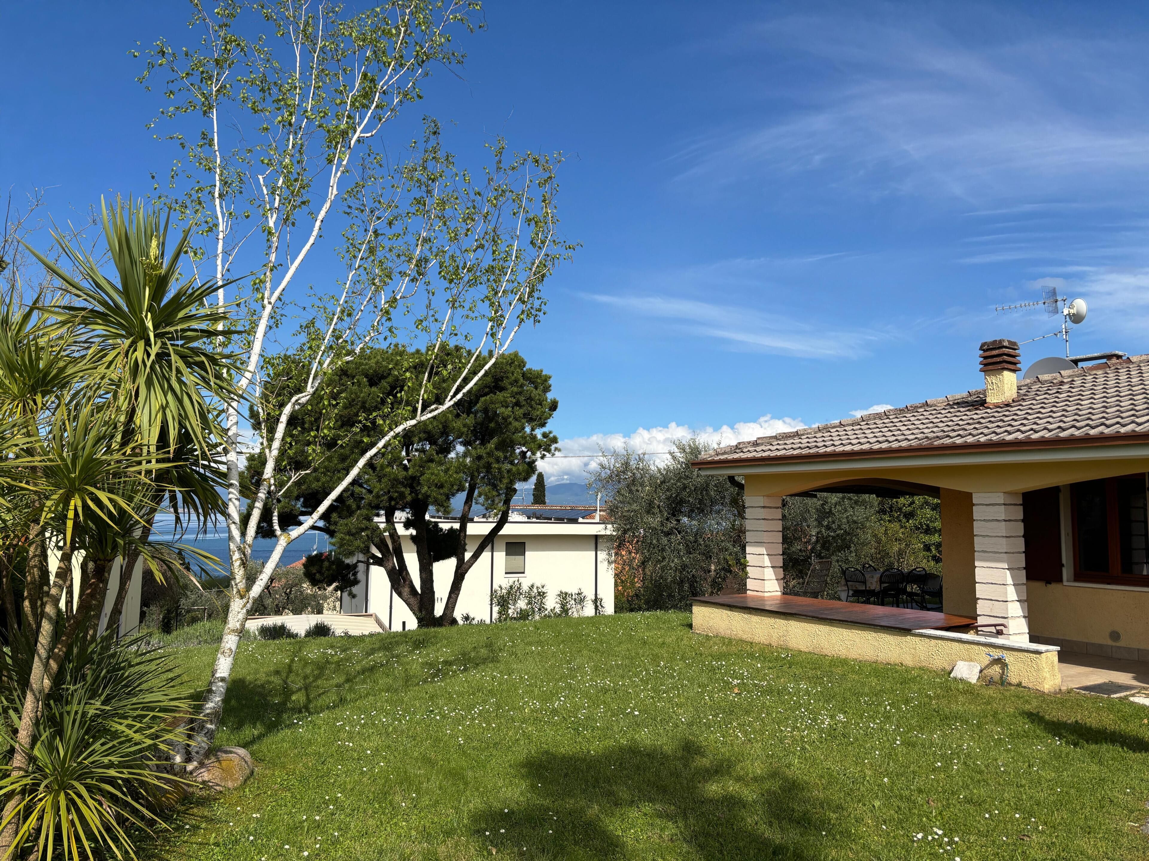 Une maison avec un toit en tuiles, un patio couvert et une cour gazonnée.