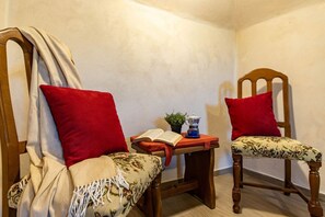 Two wooden chairs with red cushions, a small table with a book and a teapot, and a plant. - Cà dal Maestar, Nature, Hiking, and Relaxation - Valstrona - By Guestaly (Valstrona)