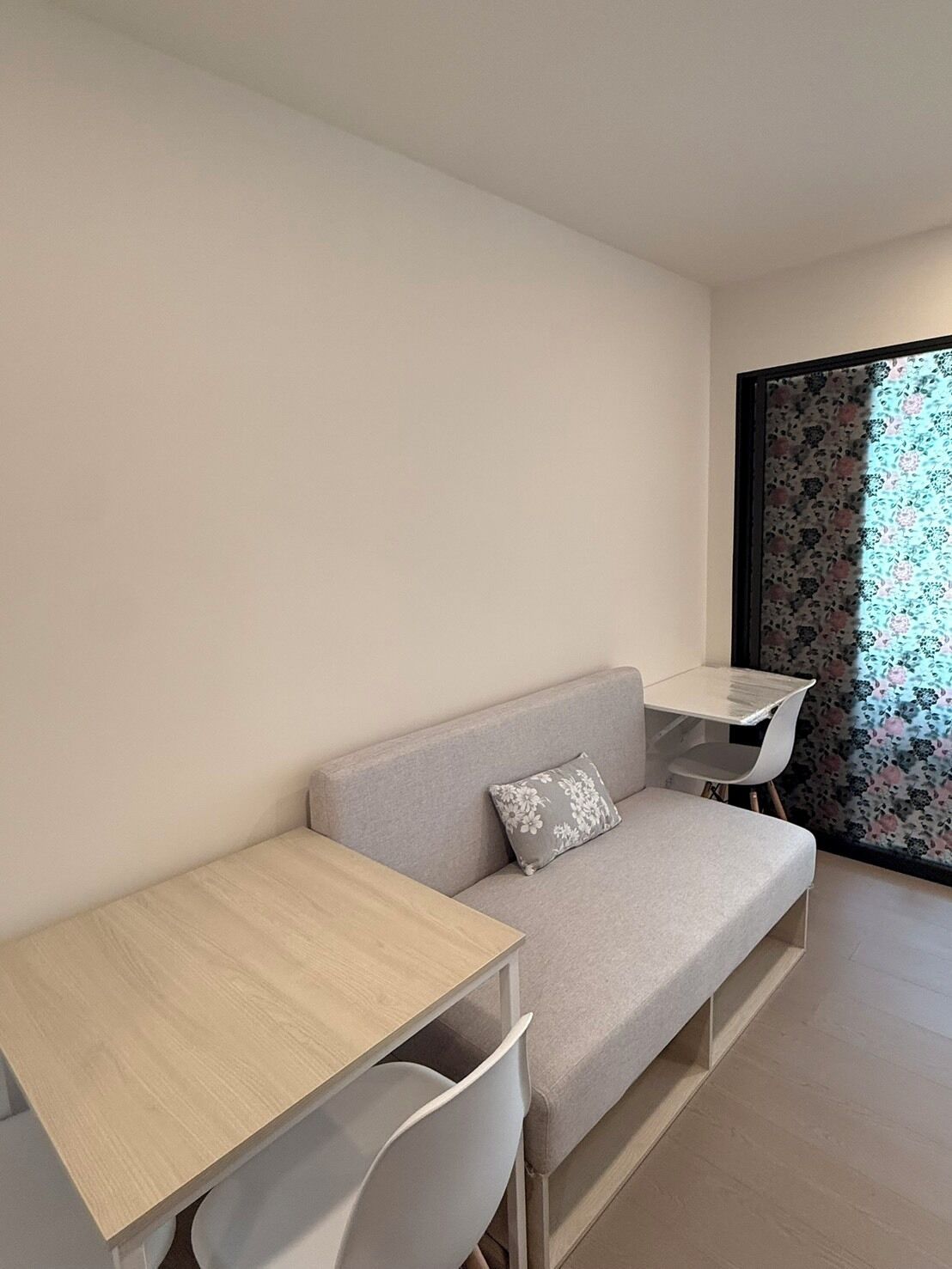 A modern room with a grey sofa, a small white table, and a white chair.