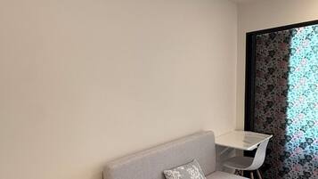 A modern room with a grey sofa, a small white table, and a white chair.