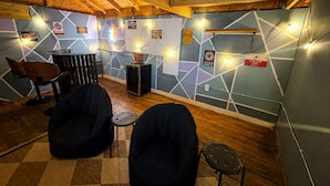 A room with a wooden ceiling, a wall with geometric patterns, a bar area, and two bean bags. - Boho Bliss Downtown Retreat - Tampa Heights -Tampa (Tampa)