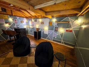 A room with a wooden ceiling, a wall with geometric patterns, a bar area, and two bean bags. - Boho Bliss Downtown Retreat - Tampa Heights -Tampa (Tampa)