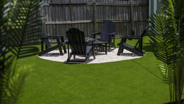 A backyard with a wooden deck, a small shed, and a lawn with a circular seating area. - Boho Bliss Downtown Retreat - Tampa Heights -Tampa (Tampa)