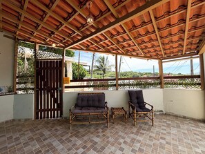 A covered outdoor seating area with a tiled floor, two chairs, and a wooden table. - Casa Silandia Tartaruga, beaches, markets and city center within walking distance; excellent location. (Armação dos Búzios)