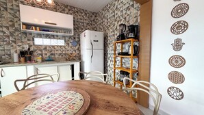 Eine Küche mit einem weißen Kühlschrank, einem Holzespeisetisch mit Stühlen und einer Wand mit geometrischen Fliesen.