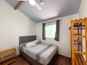 A bedroom with a bed, a wooden bench, a ceiling fan, and a window with curtains. - Casa Silandia Tartaruga, beaches, markets and city center within walking distance; excellent location. (Armação dos Búzios)