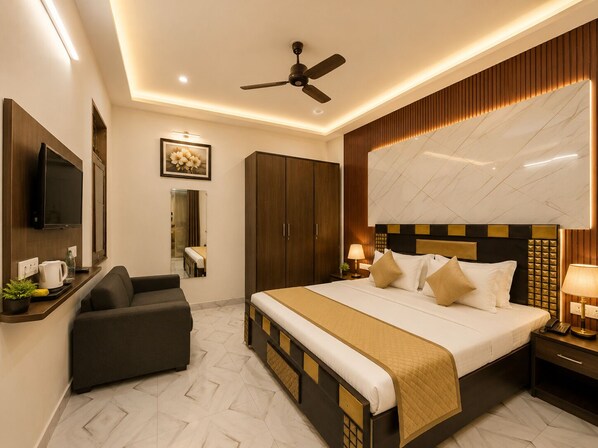 A hotel room with a bed, a sofa, a television, a ceiling fan, and a large mirror.