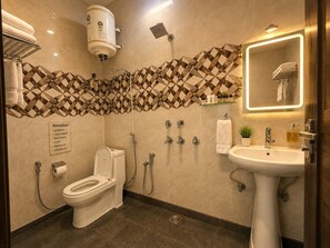 A modern bathroom with a toilet, bidet, and sink. Amenities listed include shampoo, conditioner, body wash, soap, dental kit, and shaving kit.