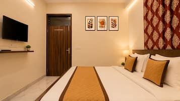 Habitación de hotel con una cama, un televisor, una puerta y tres cuadros en la pared.