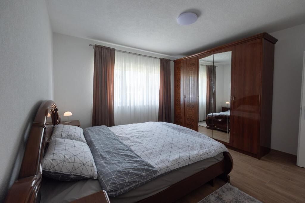 A bedroom with a bed, nightstands, a wardrobe, and a mirror.