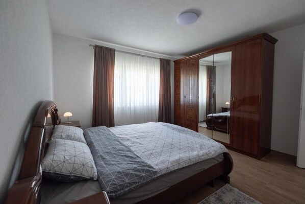 Un dormitorio con cama, mesitas de noche, armario y espejo.