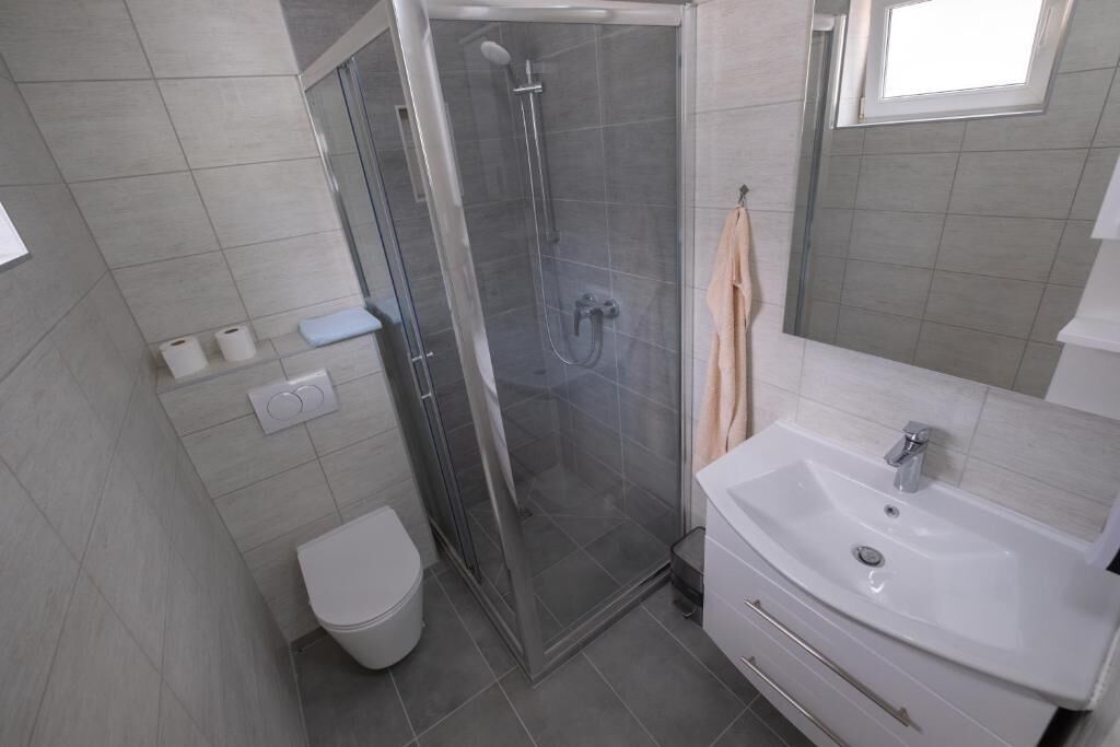 Ein Badezimmer mit Duschkabine, Waschbecken in Weiß und Toilette.