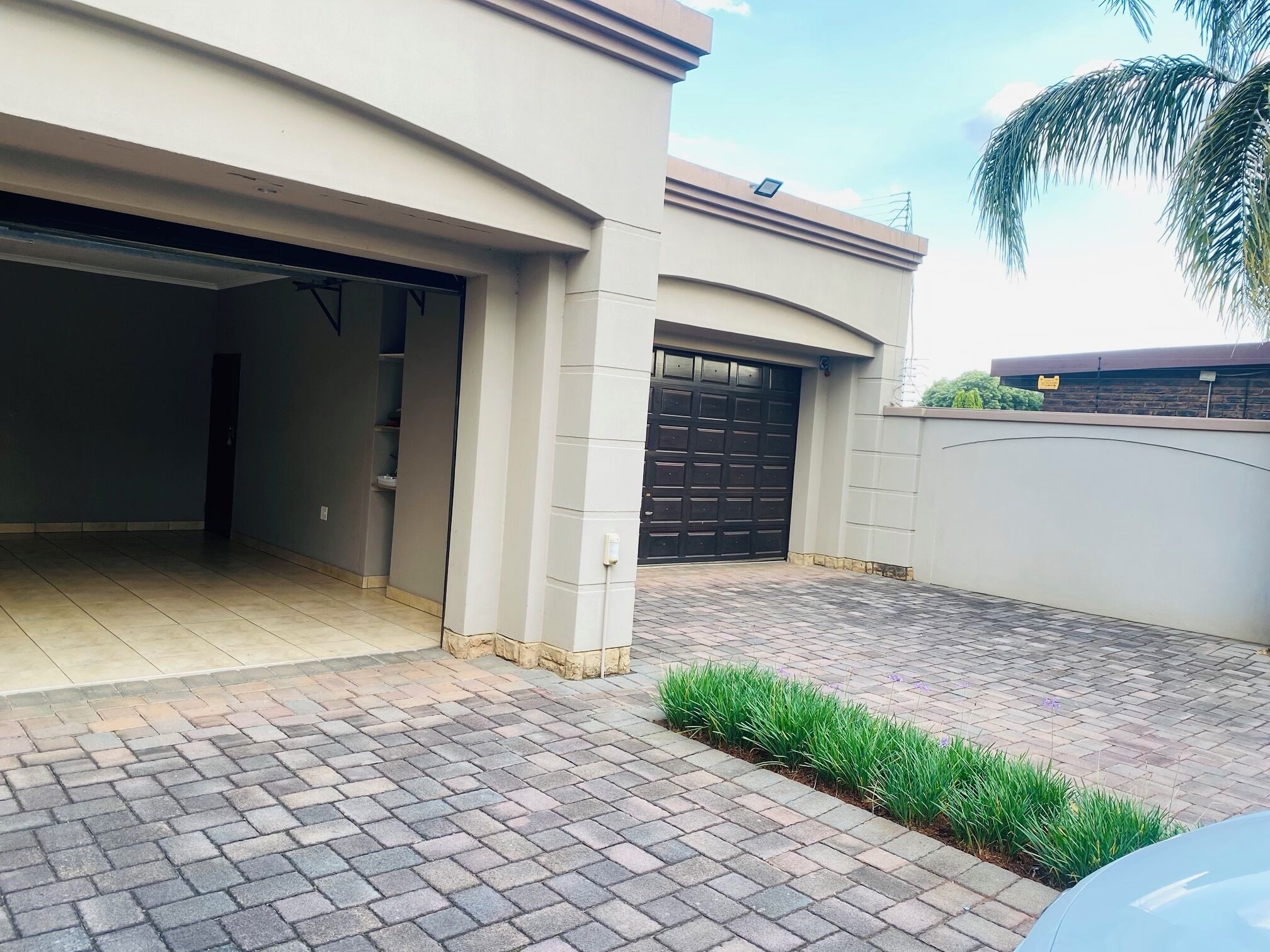 A modern house with a garage, paved driveway, and a small garden area.