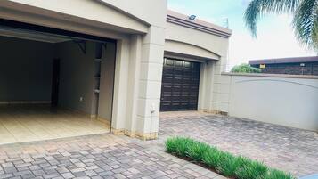 A modern house with a garage, paved driveway, and a small garden area.