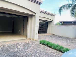 A modern house with a garage, paved driveway, and a small garden area. - OR Tambo Airport holiday home (Boksburg)