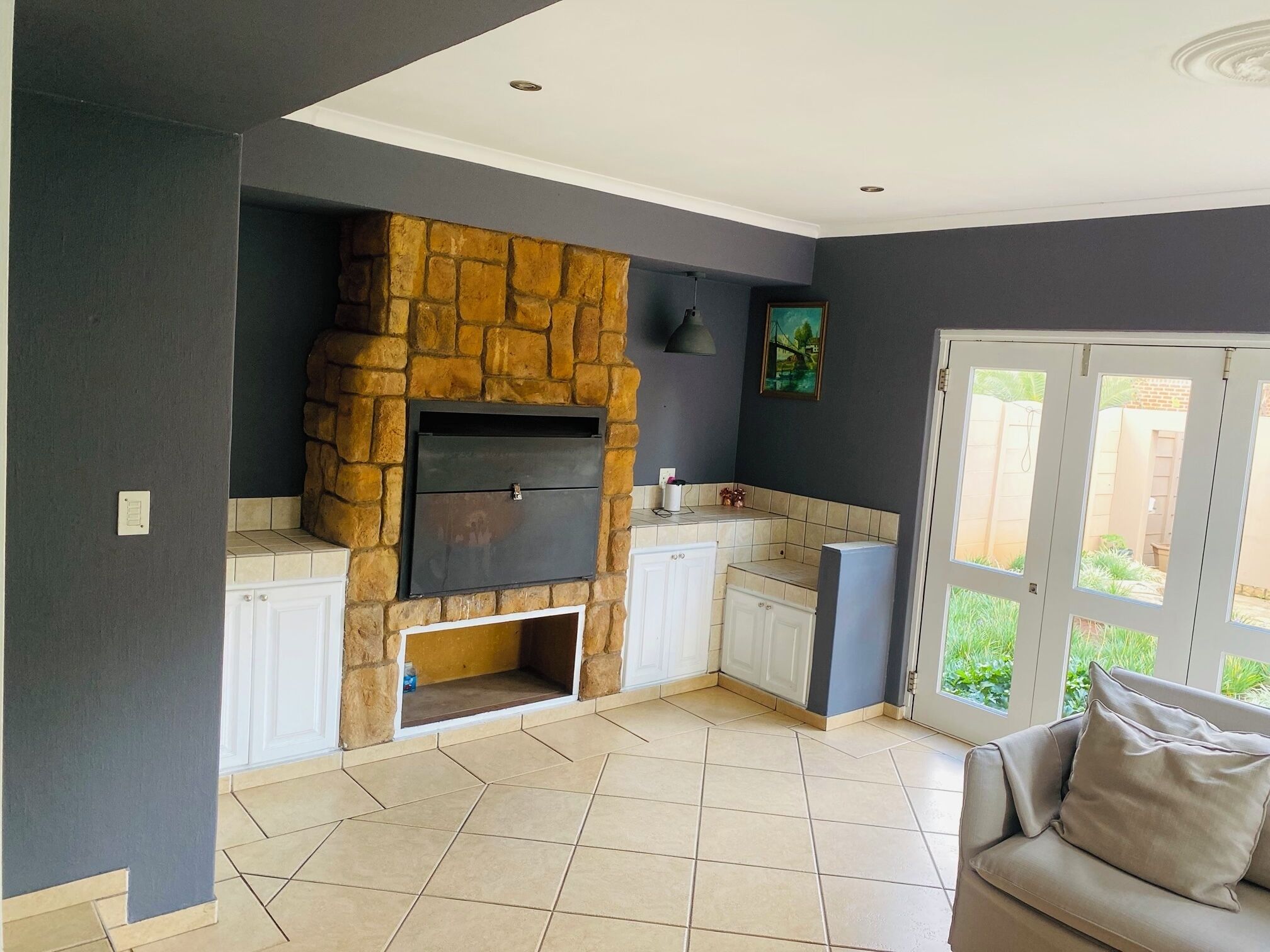 Cocina moderna con chimenea de piedra, armarios blancos y vista a zonas verdes.