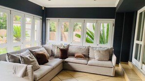 A modern living room with a sectional sofa, large windows, and a view of the outdoors.