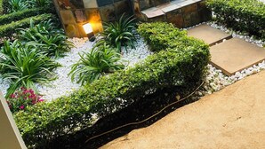 A modern outdoor seating area with a stone bench and steps, surrounded by well-maintained hedges and plants.