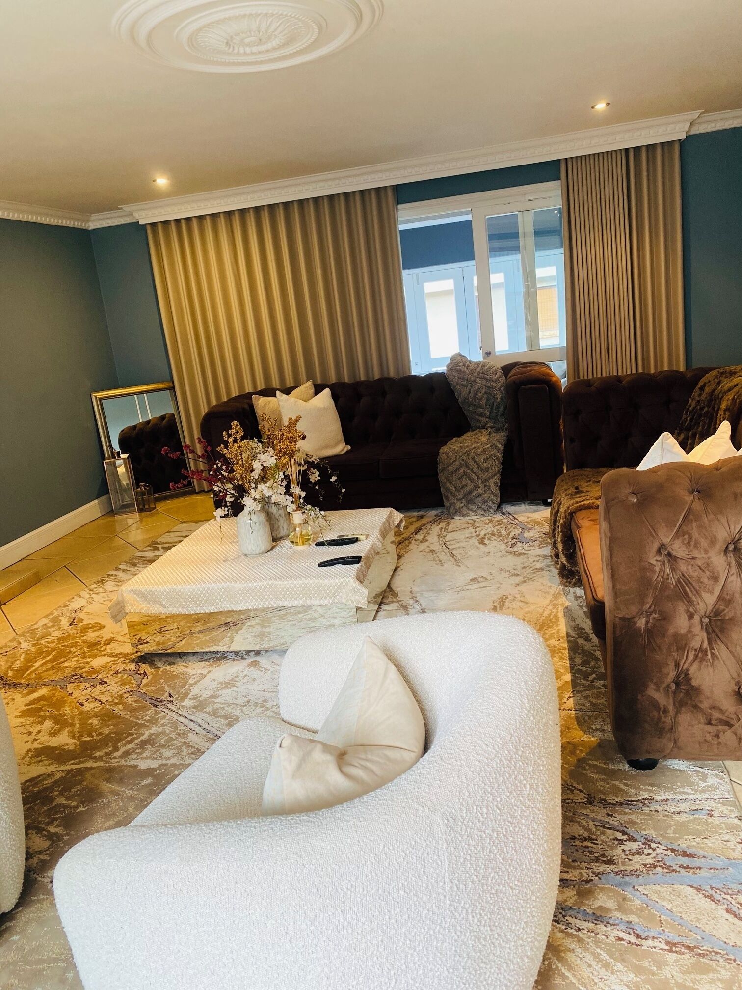 A living room with a dark-colored sofa, a white armchair, and a patterned rug.