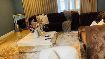 A living room with a dark-colored sofa, a white armchair, and a patterned rug.